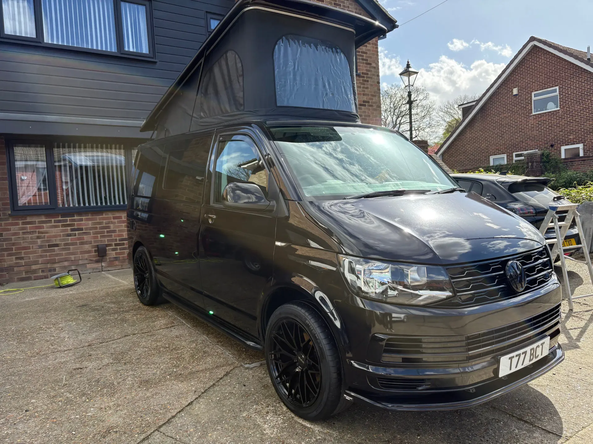 Black VW camper van with a pop-top roof on a Kent driveway before mobile remapping.